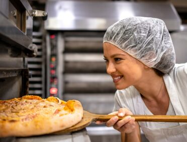baker putting bread in an overn for Learn Q Food Hygiene Safety - Protecting Your Business blog