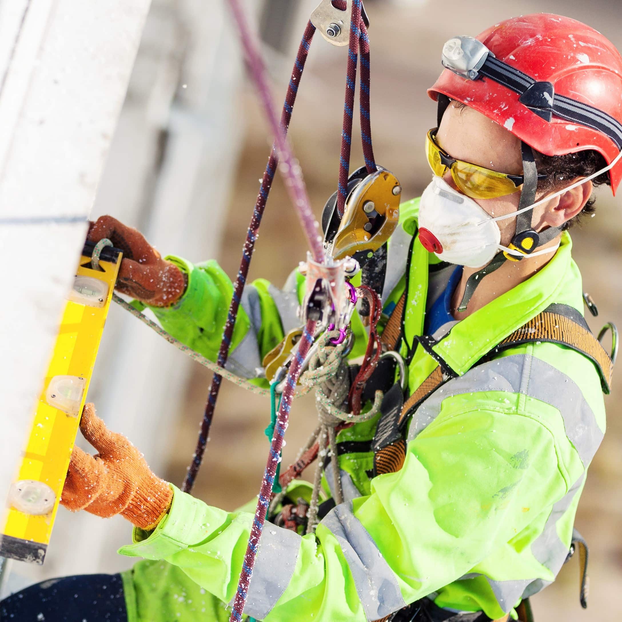 Image of Industrial Climber Measuring with Level Tube During Construction Works for Learn Q Working At Heights FAQs