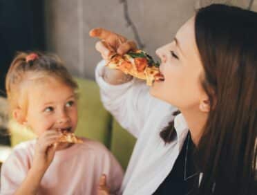 Image of Happy Mother and Daughter Eating Pizza for Learn Q The Hidden Dangers of Fast Foods blog