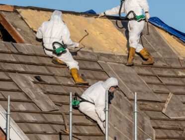 Image of men removing asbestos from a roof for Learn Q Asbestos Safety Responsibilities of Regulatory Agencies blog